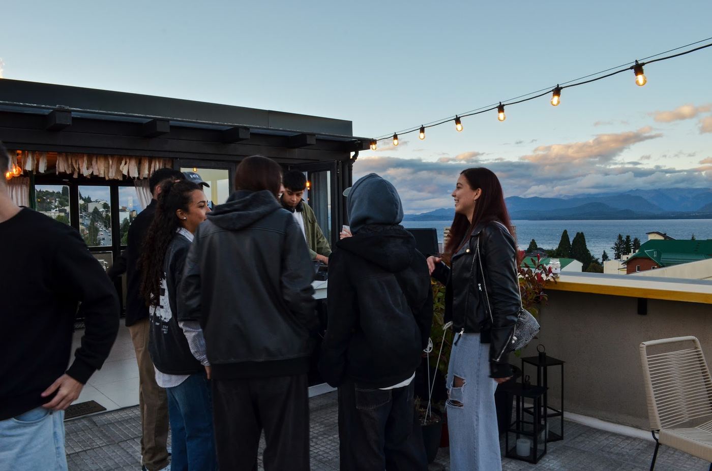 Invitados en la terraza al atardecer, bajo las guirnaldas